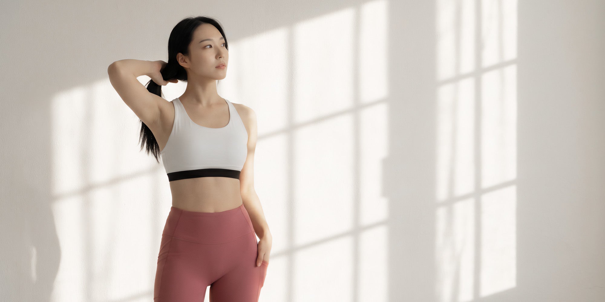 BEABLOOMのホワイトブラトップとピンクレギンスを着用した女性。着痩せ・体型カバーに優れたヨガウェア・ピラティスウェア。
